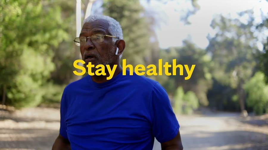 Video still of a senior man walking outside with yellow overlaying type that says Stay Healthy
